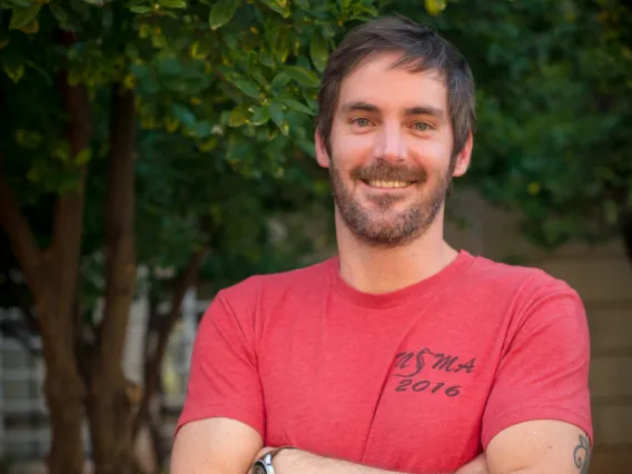 Adam Lester smiling for photo with arms crossed