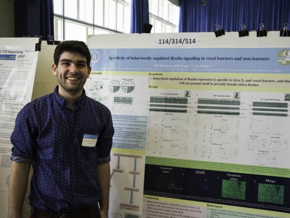 Benjamin Schwartz posing for photo in front of his research poster