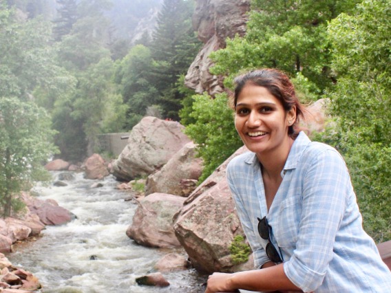 Sahana Srivathsa smiling for photo in front of river and boulders