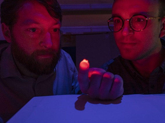 Two scientists looking at a small light