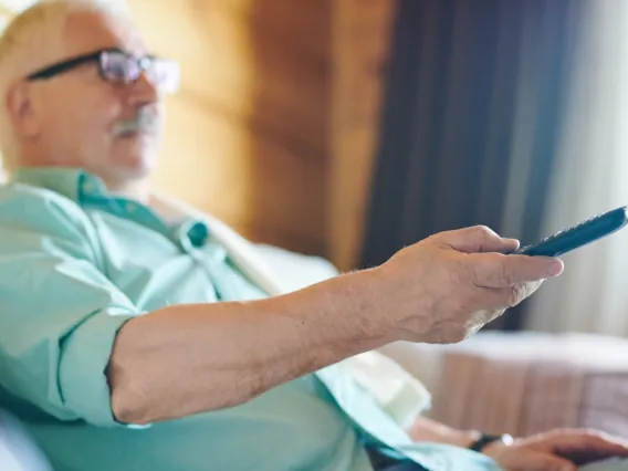 Man holding a remote and sitting on couch