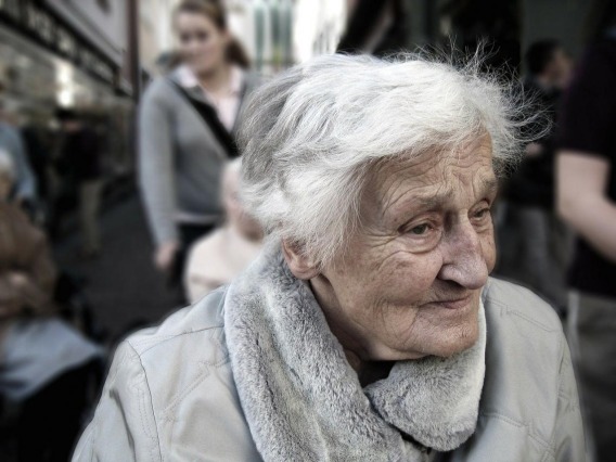 Elderly woman walking through a crowd