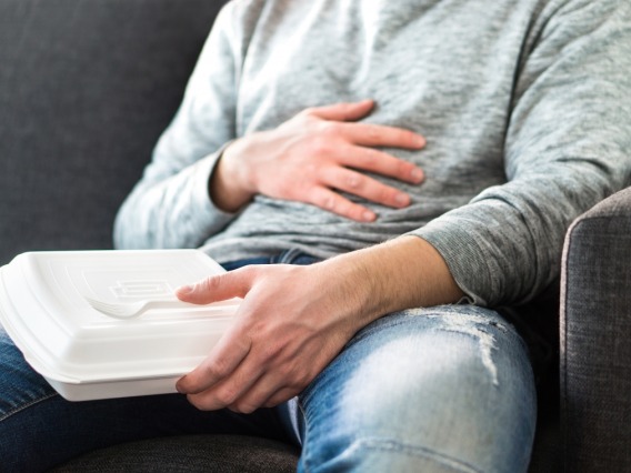 Person holding stomach after eating from food container