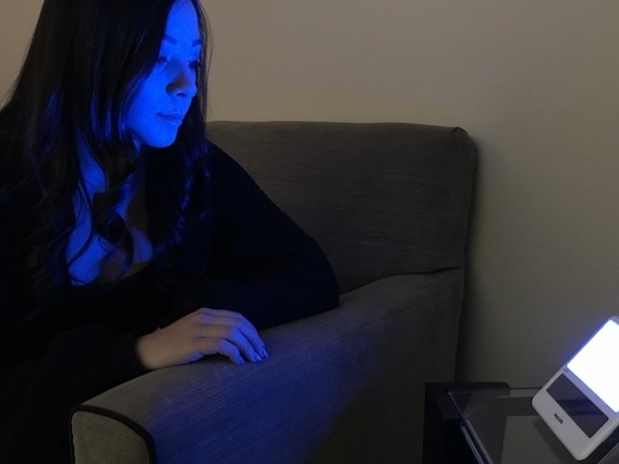 Woman sitting in front of a blue light device