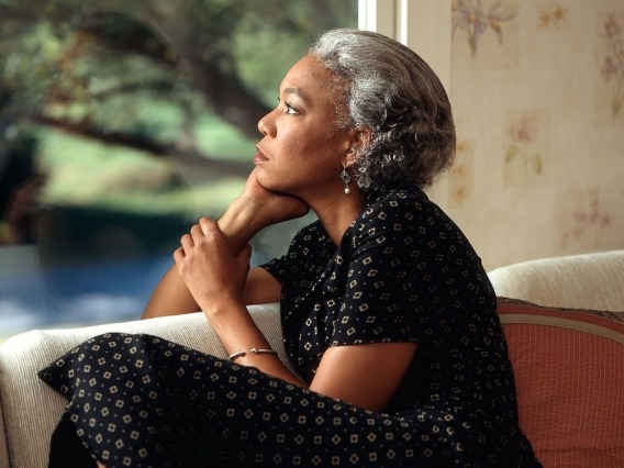 Woman sitting on couch, staring out the window pensively