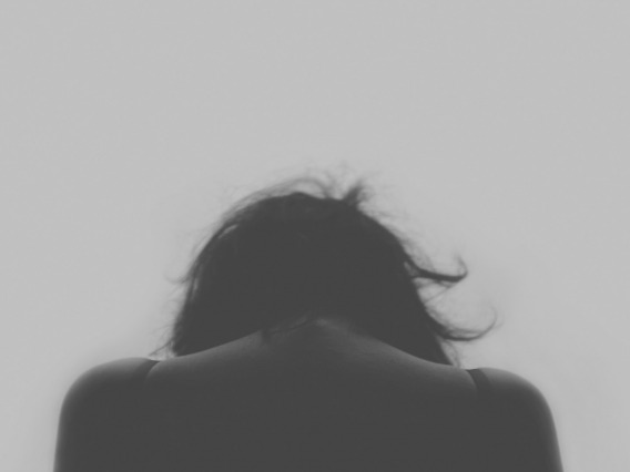 Grey photo of woman haunched over in sadness
