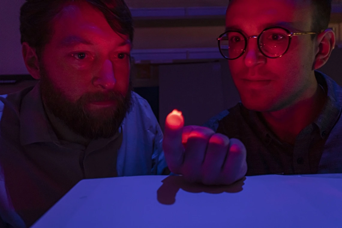 Two scientists looking at a small light