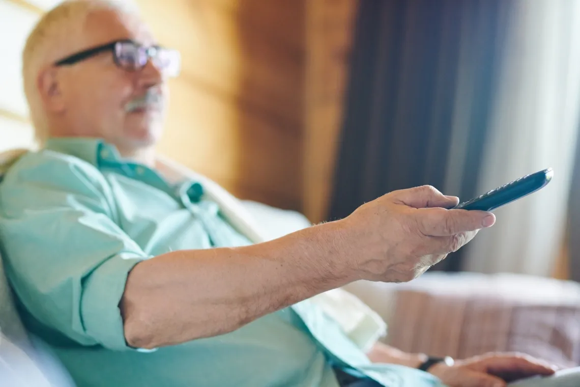 Man holding a remote and sitting on couch