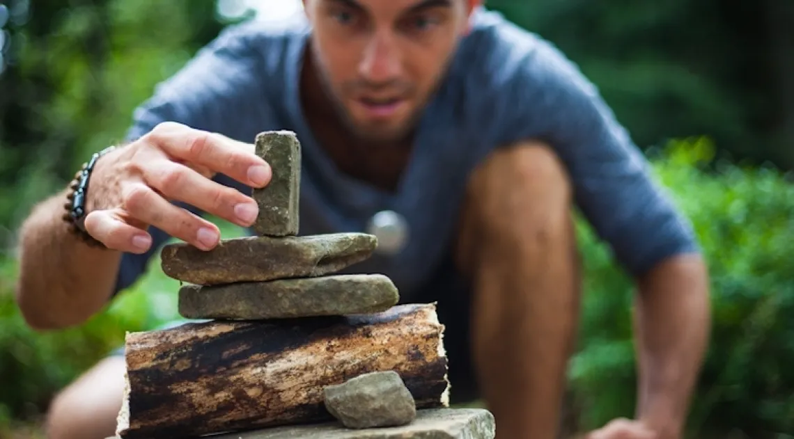 Person stacking rocks on top of each other carefully