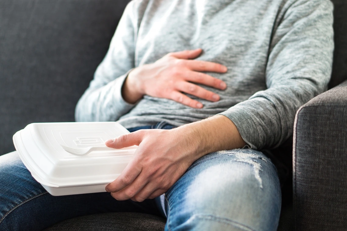 Person holding stomach after eating from food container