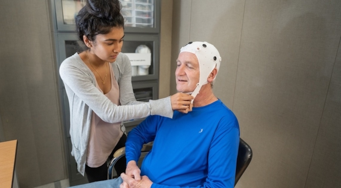 Elderly individual wearing a brain cap and participating in a test