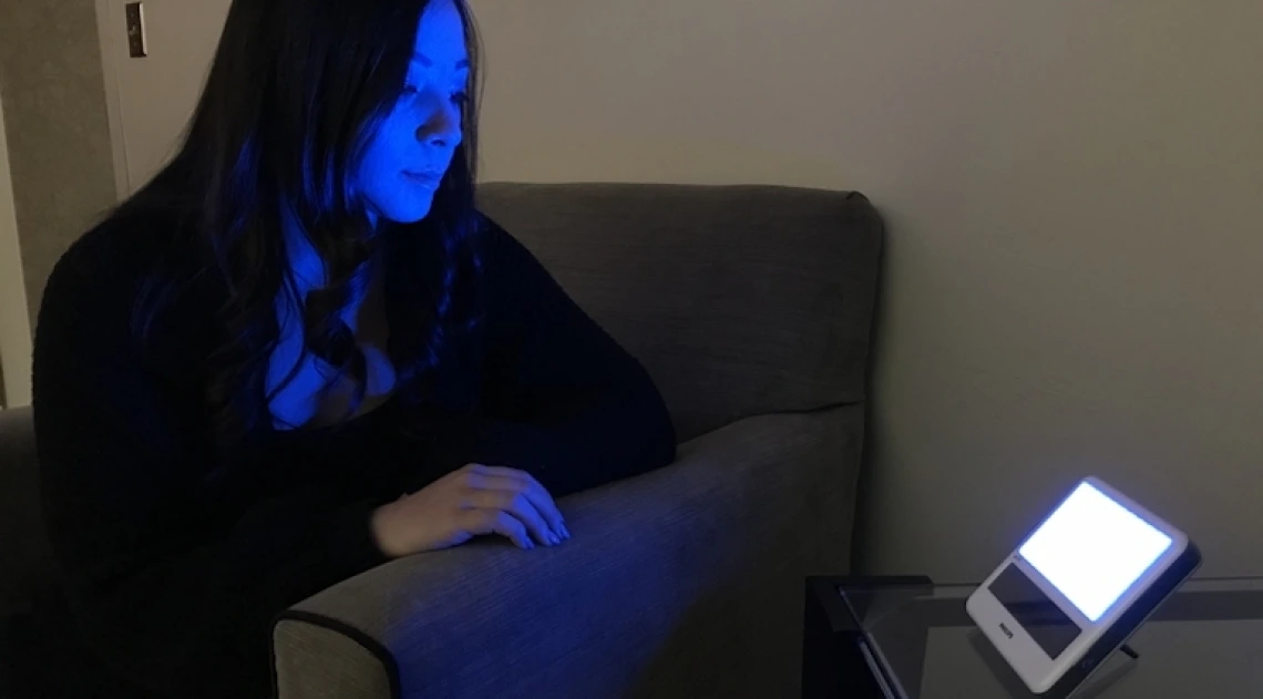 Woman sitting in front of a blue light device