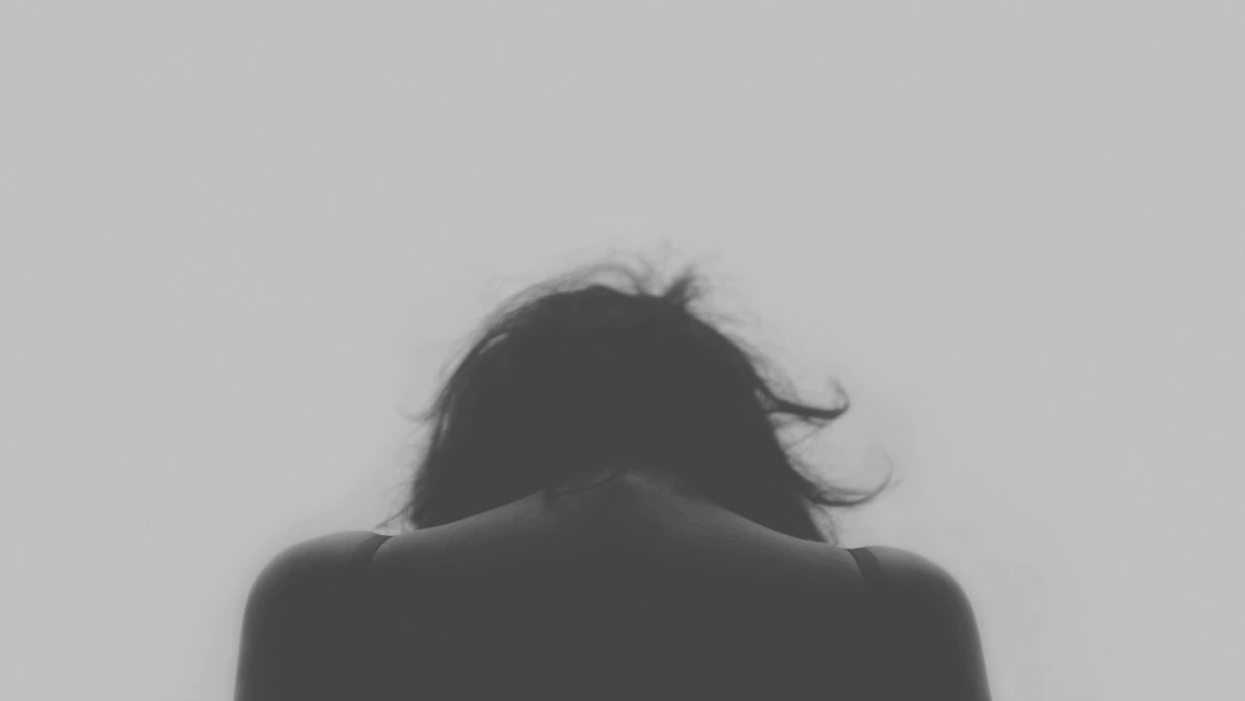 Grey photo of woman haunched over in sadness